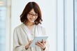 © Jumpei - 明るいオフィスでタブレットを笑顔で活用する眼鏡の日本人女性