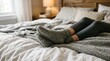 © Deamard - Close view of feet in grey knitted socks lying in bed showing a comfortable weekend lifestyle.