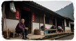 © RMartins - elderly man sitting outside traditional wooden house