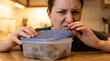 © Guilherme - Disgusted woman opening spoiled food container in kitchen