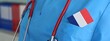 © Nadzeya - Healthcare professional in blue scrubs with French flag accent and stethoscope in a clinical