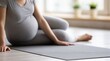 © dmmarychev - Pregnant woman sitting on yoga mat in grey sportswear