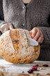 © Ina - Fresh homemade artisan bread loaf being sliced on wooden board. Rustic bakery scene with natural light. Concept of traditional baking, healthy food and homemade cooking.