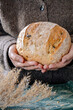 © Ina - Woman hands holding fresh homemade bread loaf. Cozy rustic scene with natural textures. Concept of comfort food, cozy home, handmade baking and slow living