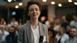 © FrameYesil - A nonbinary employee presents at a company town hall, a pronoun badge clearly visible on their jacket, diverse audience engaged and attentive under warm auditorium lighting, ideal