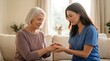 © 5 Grace Media - Caring female nurse holding hands of senior woman, offering comfort and support in a bright home setting.