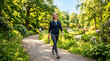 © Amiril - Happy Mature Woman Walking in Lush Sunny Park with Water Bottle