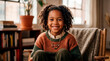 © Tom - A heartwarming portrait of a cheerful young African American girl with curly hair, smiling brightly while sitting in a comfortable armchair. The cozy indoor setting features warm lighting, a rustic kn