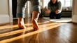 © Panca - Close up of a young baby taking their very first steps across a sunlit wooden floor towards their happy mother who is waiting with open arms