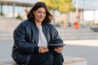 © Andrii Zastrozhnov - Woman sitting on a bench using a tablet in a black bomber jacket for remote work banner and lifestyle background