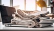 © Faustino - laptop and stack of newspapers showcasing online and print media