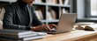 © petrrgoskov - Ambitious professional or student typing on laptop surrounded by open books in a modern library. Ideal for education, remote work, research, and female empowerment campaigns.