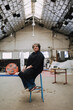 © Luciano Spinelli/Stocksy - Artist Seated in Industrial Studio