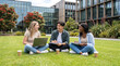 © Monktwins - International students sitting on green campus lawn and chatting together, study in New Zealand and higher education concept.