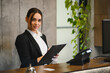 © Serhii - Friendly receptionist working at hotel front desk smiling
