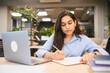 © Serhii - Indian student studying and writing in office