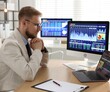 © New Africa - Financial trading specialist working at wooden desk in office