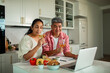 © Marko Geber - Couple enjoying virtual wine tasting and cooking in home kitchen
