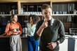 © Miljan Živković - Young man holding coffee mug in office kitchen with colleagues