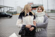 © Светлана Лазаренко - Two women chat and smile in a parking lot on a cool day as they enjoy each other's company while dressed for the weather