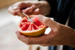 © Westend61 - Hand scooping fresh pink grapefruit with a spoon