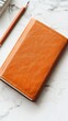 © Роксолана Гордієвич - A tan leather journal rests on a marble background beside a sharpened pencil, symbolizing creativity and planning.