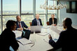 © DragonImages - Wide shot of middle aged business team discussing strategy during oil industry meeting in boardroom, reviewing reports and laptop. Ideal for energy leadership, corporate planning, investment
