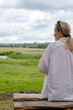 © Ina - Middle aged woman sitting outdoors and looking across countryside landscape during picnic getaway. Quiet contemplation, relaxation and peaceful connection with nature concept.