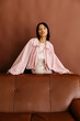 © Tania Cervian/Stocksy - Woman behind brown leather couch