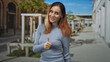 © Krakenimages.com - Woman redhead in a ribbed sweater giving thumbs up with visible thumb and smile on a sunny street; confidence encouragement approval support.