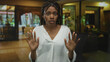 © Krakenimages.com - African american woman with braided hair hands raised palms out in hotel building lobby facing camera, white shirt visible; concern caution.