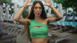 © Krakenimages.com - Woman sticks tongue out with hands raised and bare midriff visible at poolside building; playful confidence.