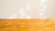 © Enes - Completely empty smooth honey-toned wooden table surface with soft blurred bright background and gentle bokeh spots, product display mockup concept, presentation background