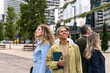 © Koldo_Studio - Diverse business people with positive expressions looking up, standing on a city street with modern office buildings, representing ambition and future vision