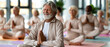 © Olga Ко - Happy senior man with white beard meditating in lotus pose during group yoga class. Active retirement, health, mindfulness and wellness concept.