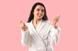 © Pixel-Shot - Young woman in bathrobe with hair spray making heart gesture on pink background