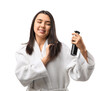 © Pixel-Shot - Young woman in bathrobe applying hair spray on white background