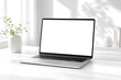 © MUHAMMAD HBIB - Modern silver laptop with a blank white screen on a minimalist white desk, bathed in natural light with a green plant and subtle shadows.
