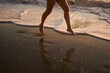 © Thomas - Detailaufnahme von Frauenbeinen, die bei romantischem Sonnenuntergang barfuß am Strand durch das flache Wasser und die Wellen laufen.