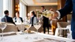 © ALLmost - Waiter pouring white wine into a crystal glass at an upscale restaurant with blurred patrons in the background, highlighting fine dining service.
