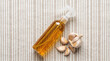 © Viskia - Garlic infused oil spray bottle and fresh garlic cloves on a striped linen background