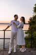 © Тарас Белецкий - Young couple embracing on a wooden pier at sunset with a serene lake background