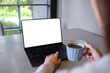 © Farknot Architect - Mockup image of a woman working and typing on laptop computer with blank white desktop screen while drinking coffee