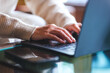 © Farknot Architect - Closeup image of a woman working and typing on laptop computer with mobile phone on the table