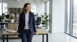 © Sofia - Friendly female assistant smiling in modern office. Confident businesswoman leaning on desk in bright workspace. Corporate career and positive workplace concept