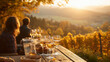 © Alena - Golden hour in a vineyard on a hillside, people sitting on the benches at a long wooden table set for a young wine (Federweißer) tasting outdoors