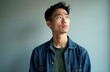 © miss irine - Young Asian man looks up thoughtfully. Concerned guy with furrowed brow considers decision, pondering problem. He has doubt, thinking about future challenges or options.