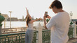 © blueringmedia - Man Taking Smartphone Photo of Woman Posing by Riverside Temple