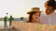 © blueringmedia - Young Asian Couple Reading a Paper Map by the Riverside at Sunset