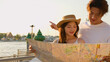 © blueringmedia - Young Asian couple looking at map by riverside at sunset in Bangkok